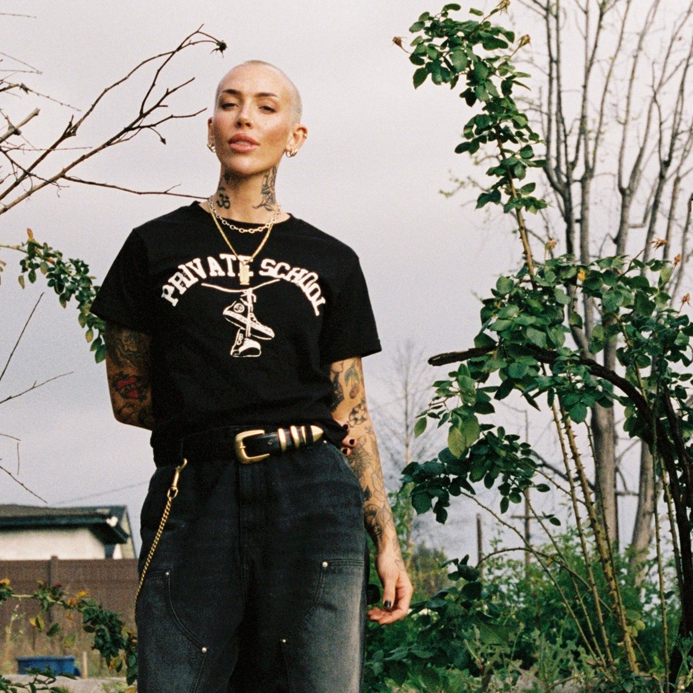 Person standing on a brick path with greenery and a wooden sign in the background